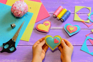 Crafting using felt with child making felt hearts from the A4 Assorted Colour Acrylic Felt Sheets 15 pack